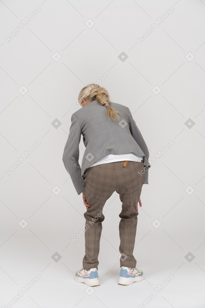 Vista traseira de uma senhora idosa de terno agachada