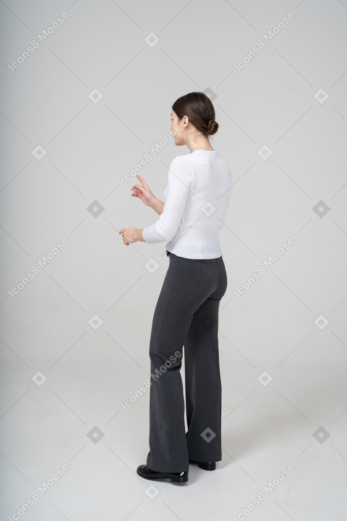 Side view of a woman in black pants and white blouse gesturing