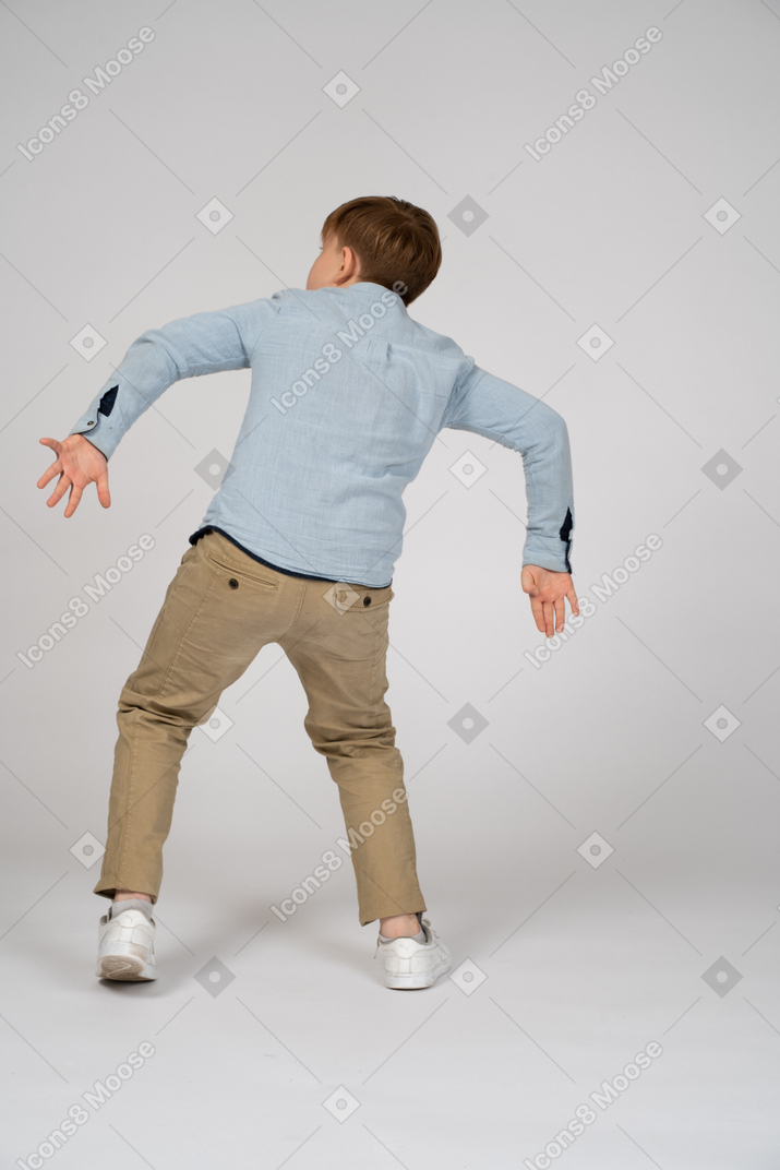Back view of a young boy doing a weird walk