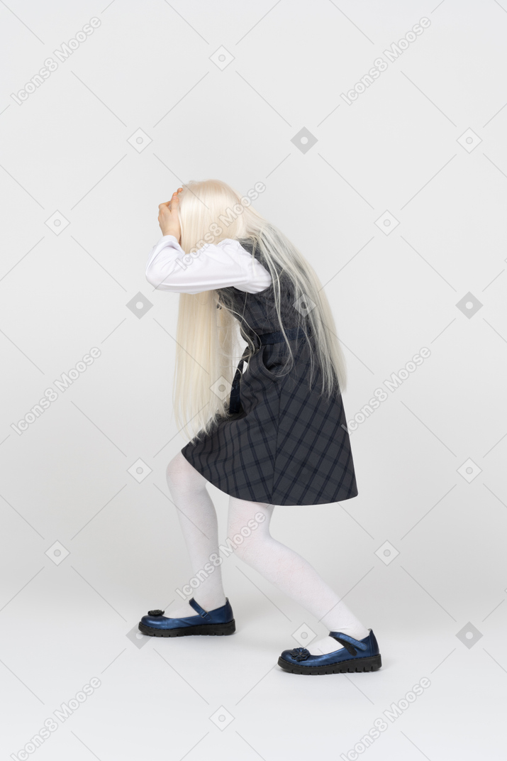 Side view of a schoolgirl holding her head