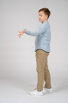 Vista lateral de um menino apontando para algo com a mão
