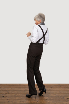 Three-quarter back view of a scared old lady in office clothing
