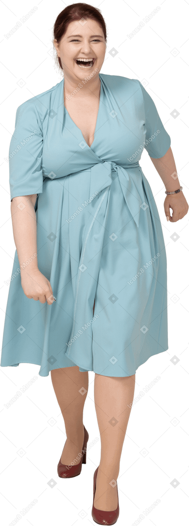 一个快乐的女人穿着蓝色裙子走路的前视图