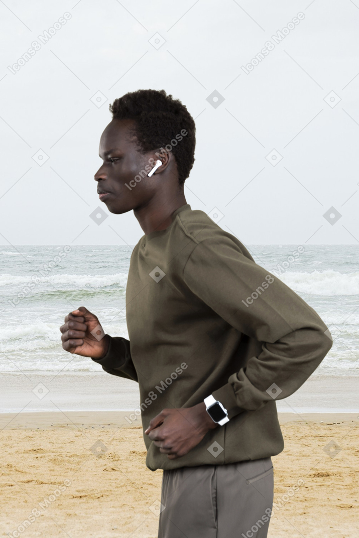 A black man running on the beach with earphones