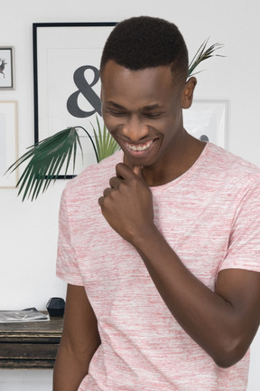 A smiling young black man in a pink t - shirt