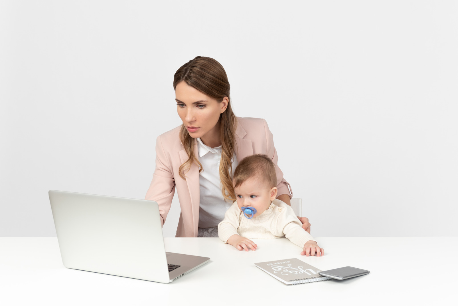 Young mom working on laptop and babysitting
