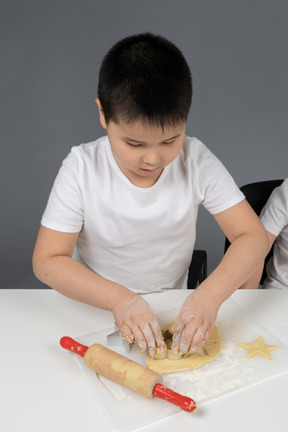 Ein kleiner junge schneidet einen lebkuchenmann aus