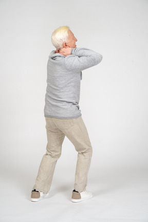 Back view of man standing with his hands on the back of his neck