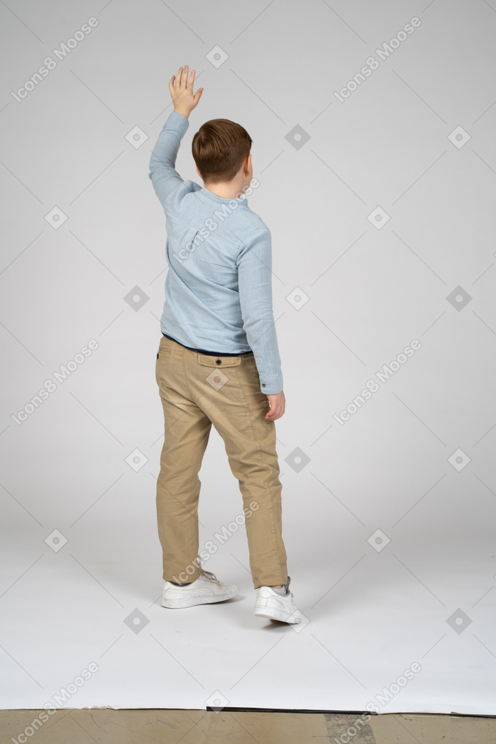 Vista trasera de un niño saludando