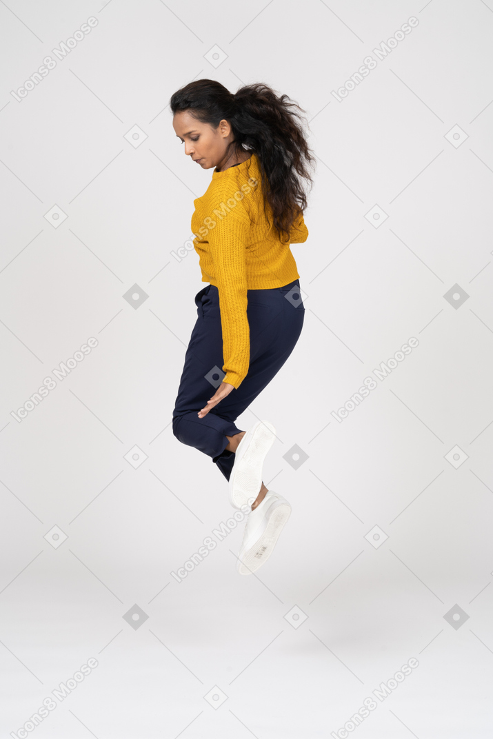 Rear view of a girl in casual clothes jumping and trying to touch her foot