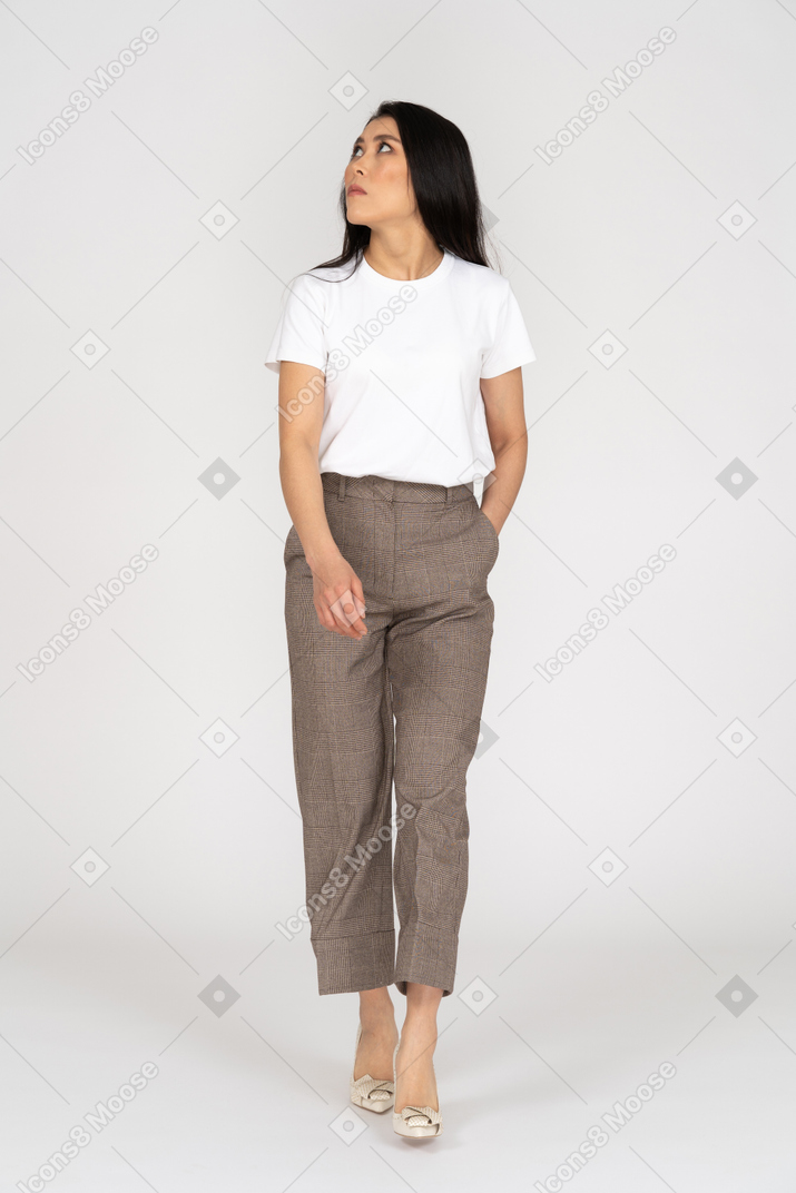 Front view of a serious young woman in breeches putting hand in pocket
