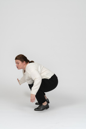 Side view of a plump woman in casual clothes squatting