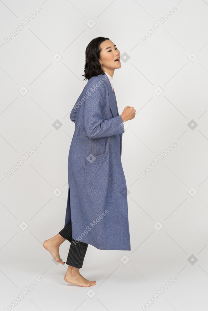 Side view of young woman in coat jogging