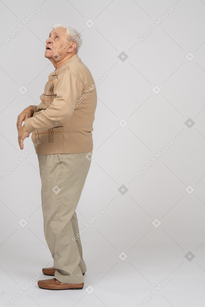 Seitenansicht eines beeindruckten alten mannes in freizeitkleidung, der nach oben schaut