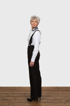 Full-length if an old female in office clothes turning back