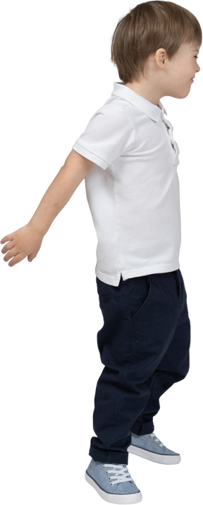 Side view of a boy stepping forward with hands behind his back