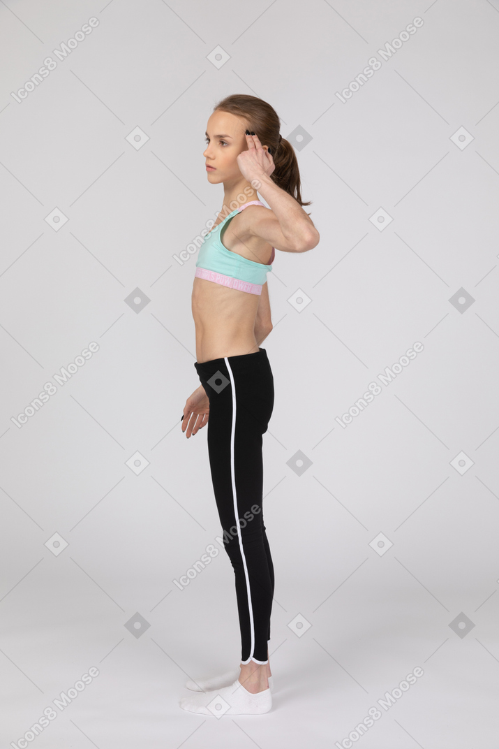 一个年轻的女孩，在运动服摸头的侧视图