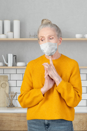 A worried elderly lady standing in the kitchen