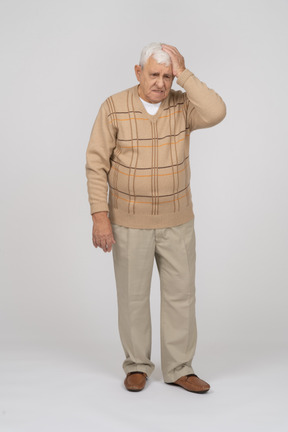 Front view of an old man in casual clothes suffering from headache