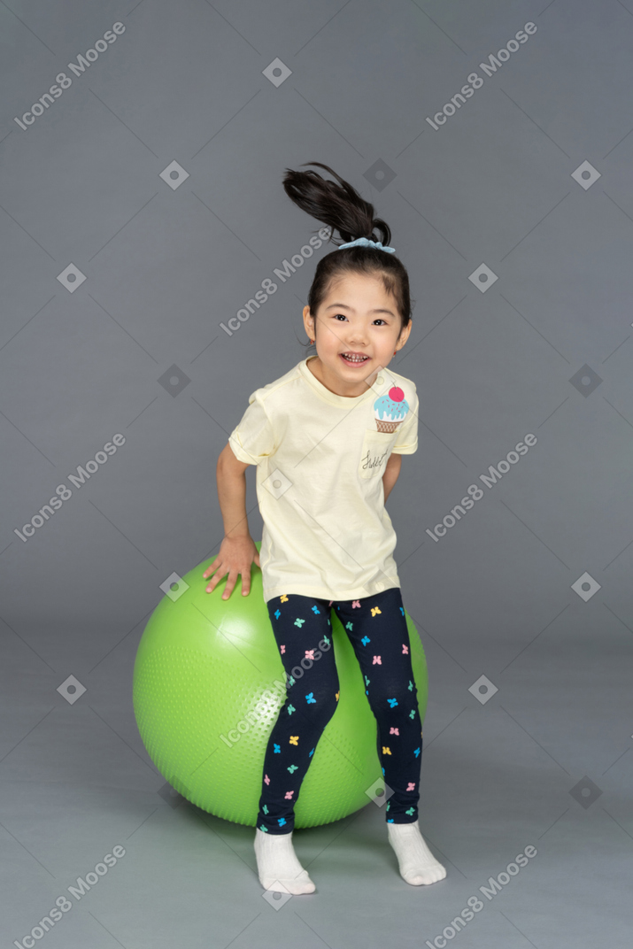 跳上绿色健身球的小女孩
