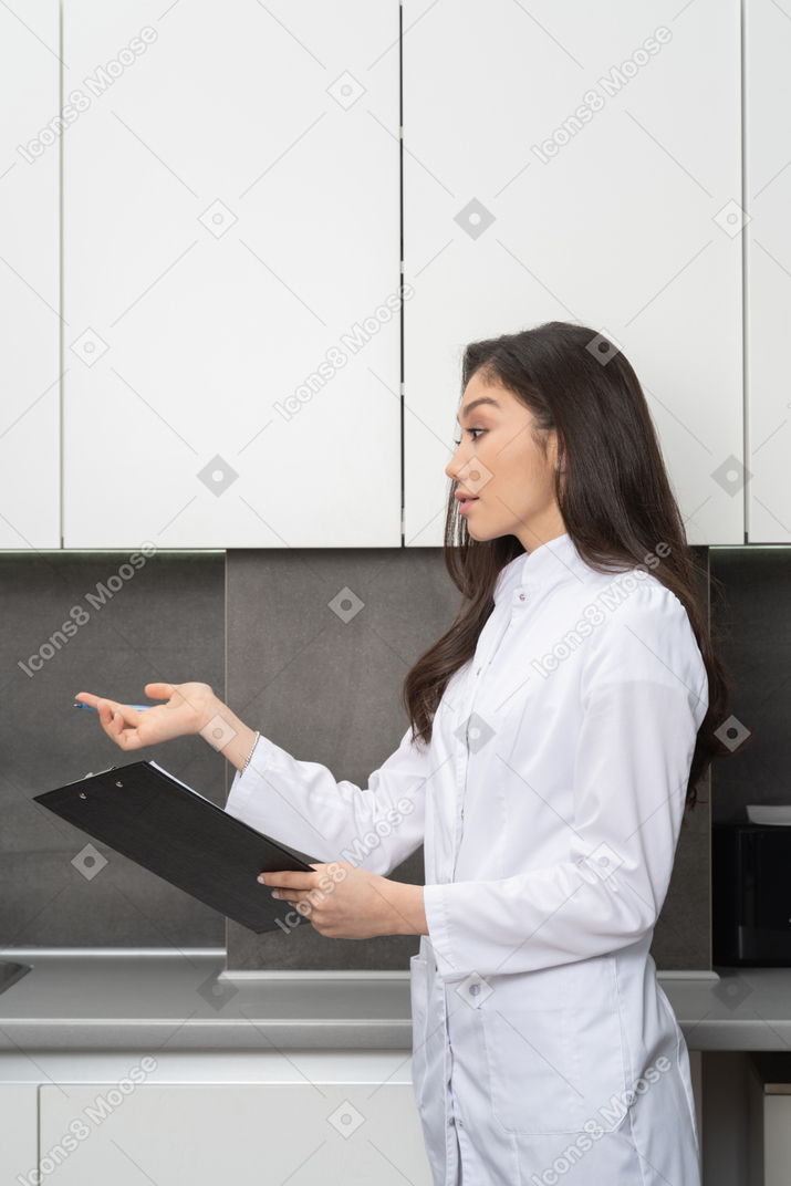 Vista de tres cuartos de una doctora sosteniendo una tableta y dando un consejo