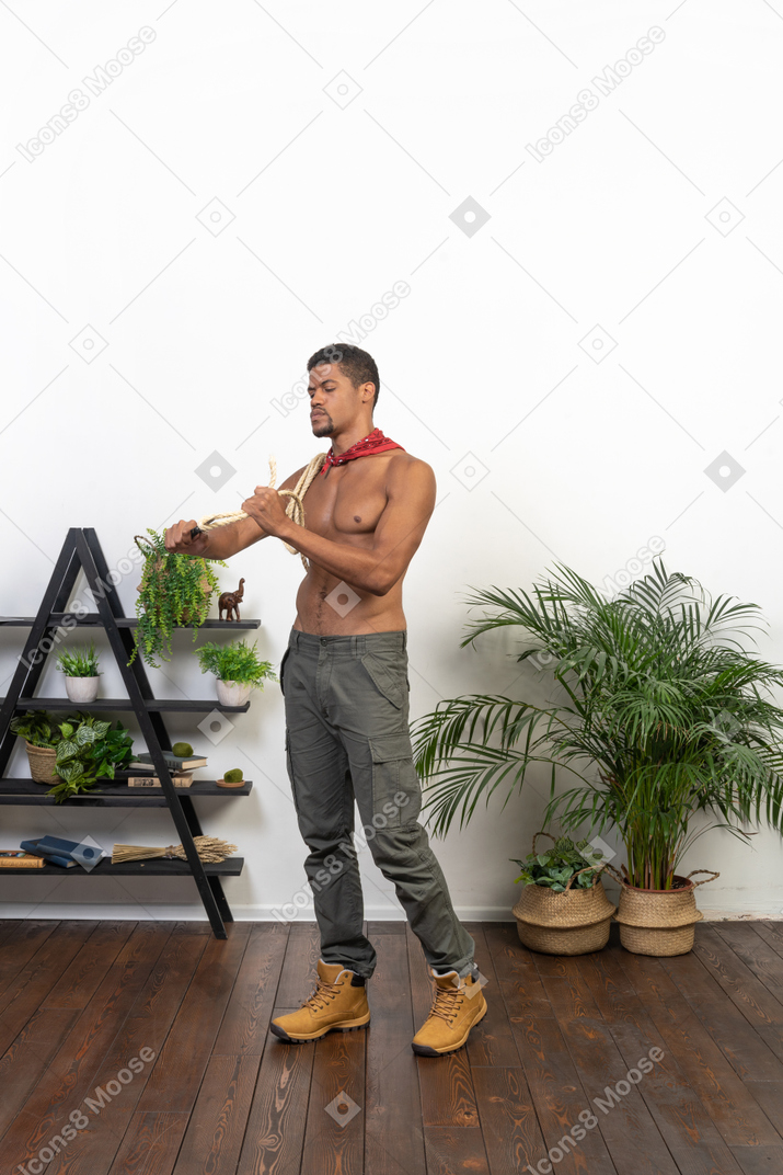 Athletic man standing and cutting rope with a blade