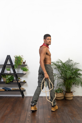 Homme musclé avec une corde à la main en regardant la caméra