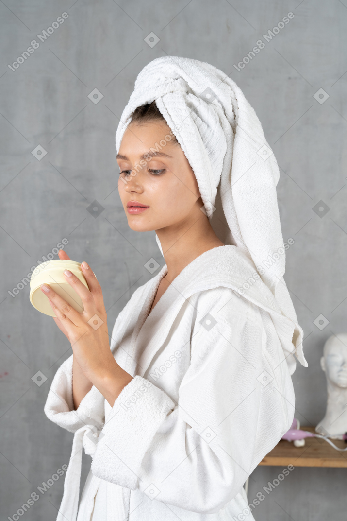 Ritratto di una donna in accappatoio che applica crema per le mani