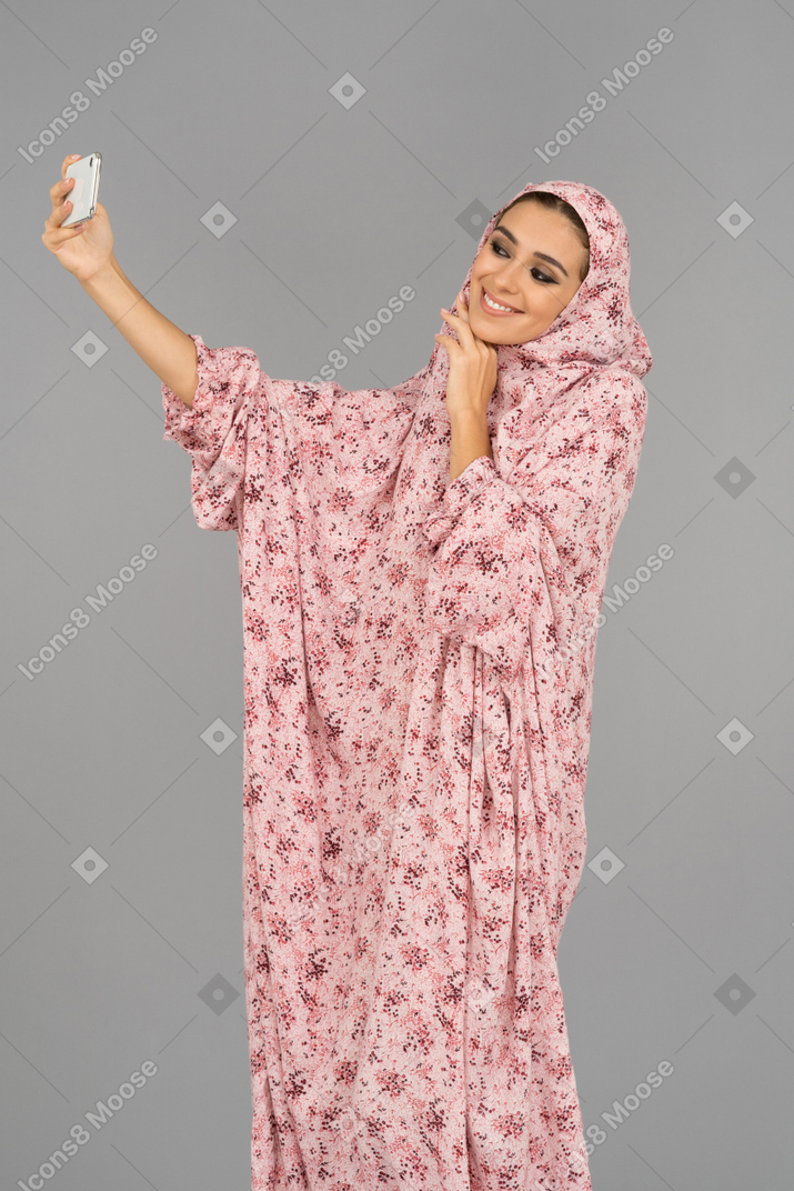 Covered young woman taking selfie