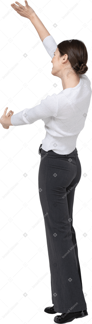 Vista laterale di una donna in pantaloni neri e camicetta bianca che mostra le dimensioni di qualcosa