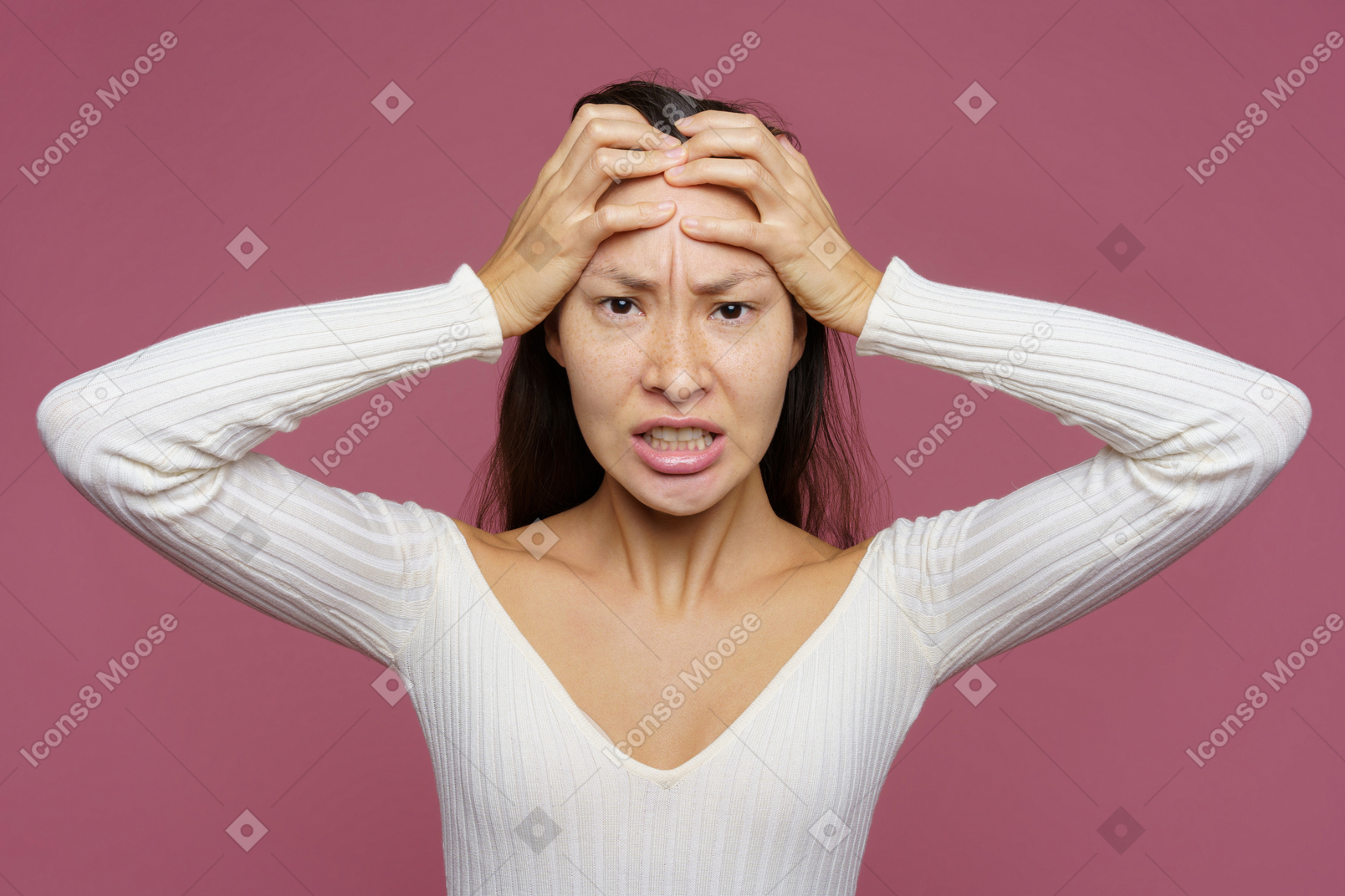 Vue de face d'une femme aux cheveux noirs en colère touchant la tête et regardant avec colère la caméra