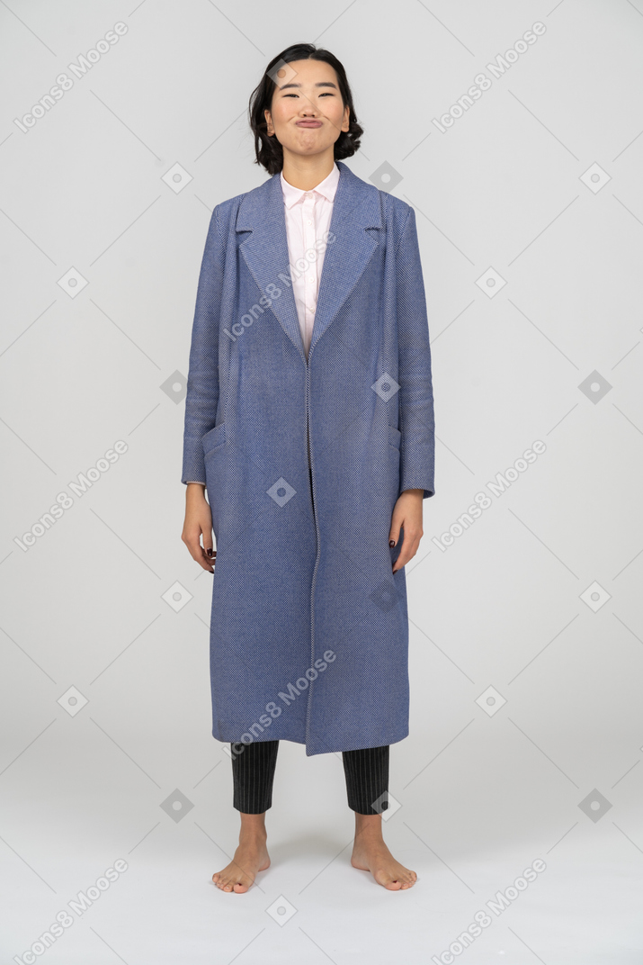 Женщина в синем пальто делает утиное лицо
