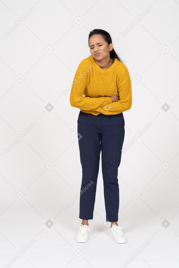 Vista frontal de una niña en ropa casual que sufre de dolor de estómago
