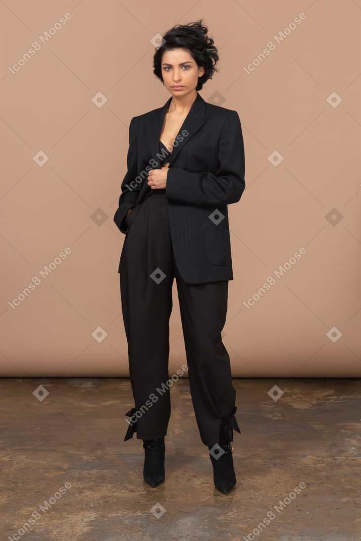 Вид спереди деловой женщины в черном костюме, серьезно смотрящей в камеру