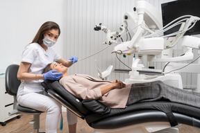 Longitud total de una dentista curando a su paciente acostada en un gabinete de hospital