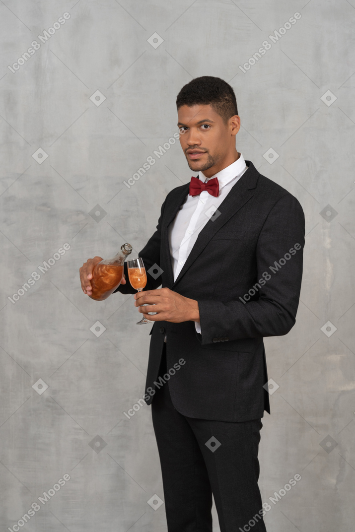 Young man pouring liquid into a glass and looking at camera