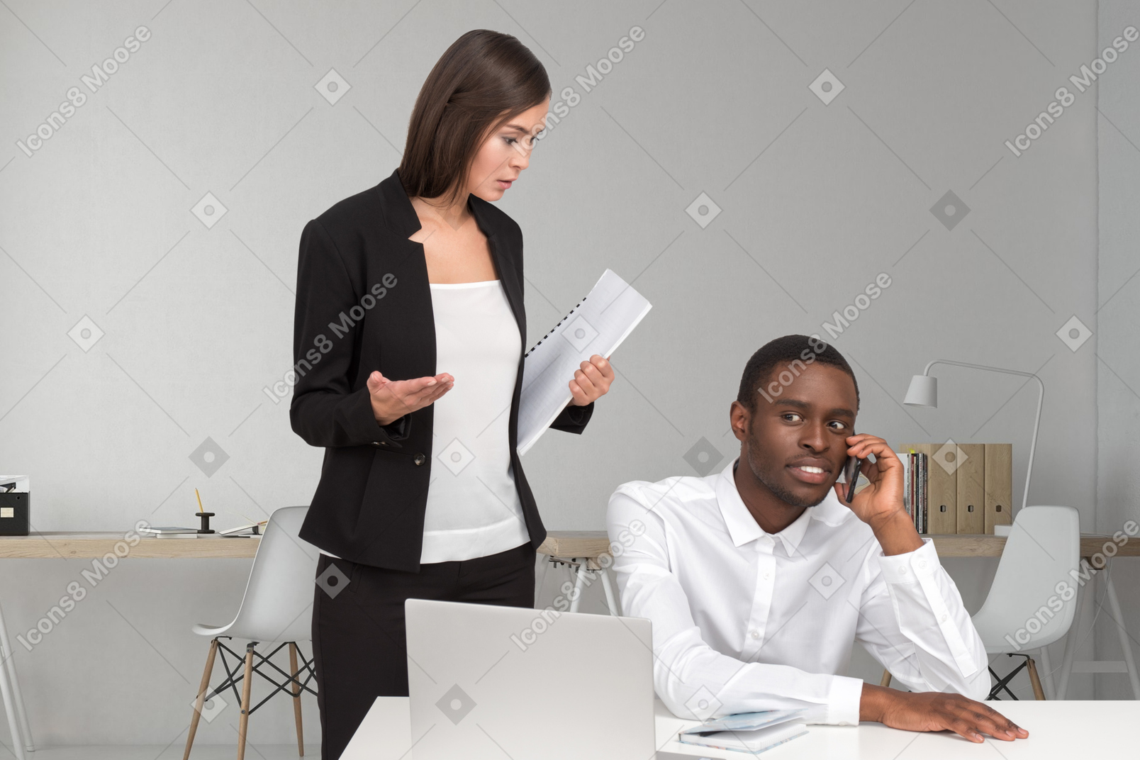 Confused female boss looking at employee talking on phone
