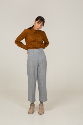 Vista frontal de una joven mujer asiática en calzones y blusa tocando la espalda