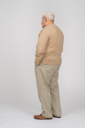 一位身穿休闲服、双手插在口袋里站着的老人的侧视图