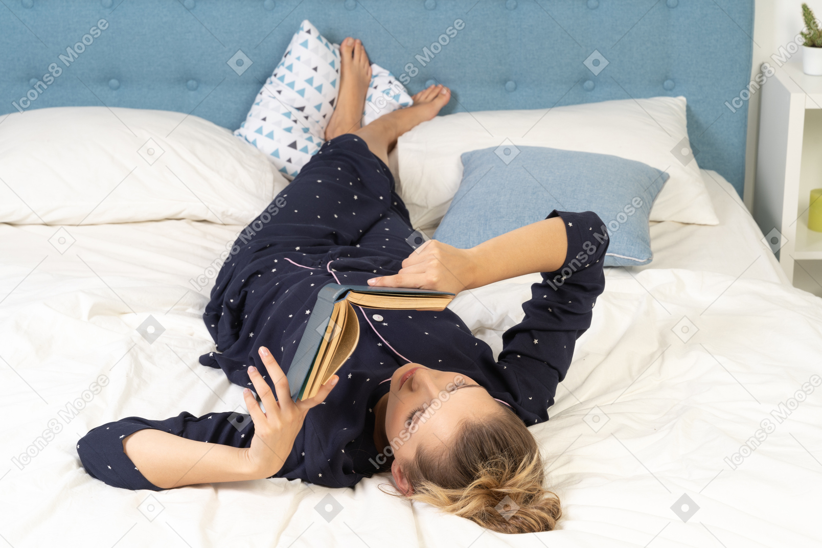 В полный рост скучающая девушка пытается читать книгу в постели