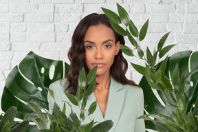 Jeune femme afro entourée de feuilles vertes