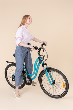 A woman standing next to a blue bicycle