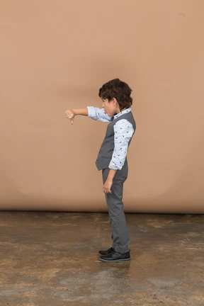 Side view of a boy in grey suit showing thumb down