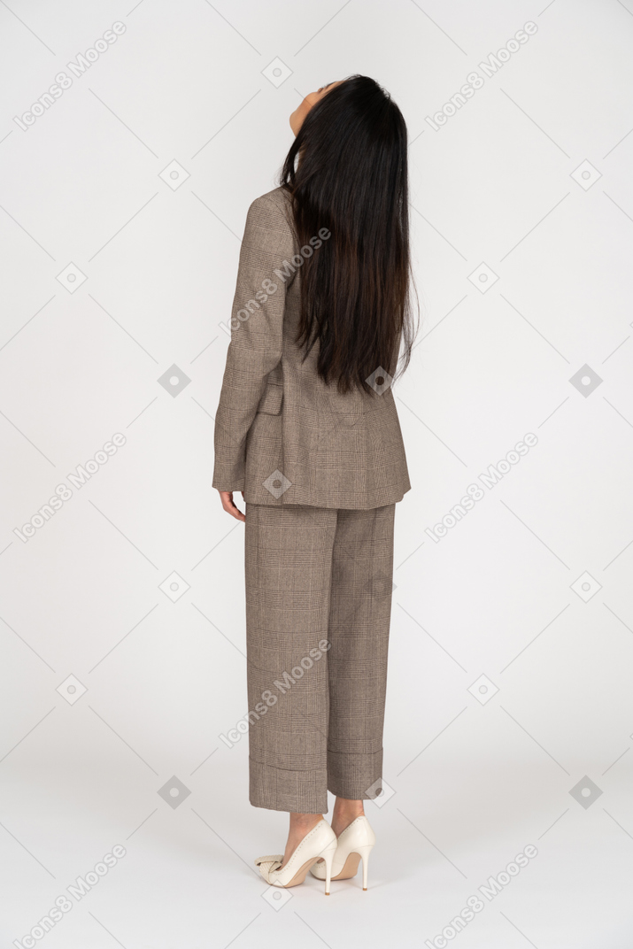 Vista de três quartos das costas de uma jovem de terno marrom jogando a cabeça para trás