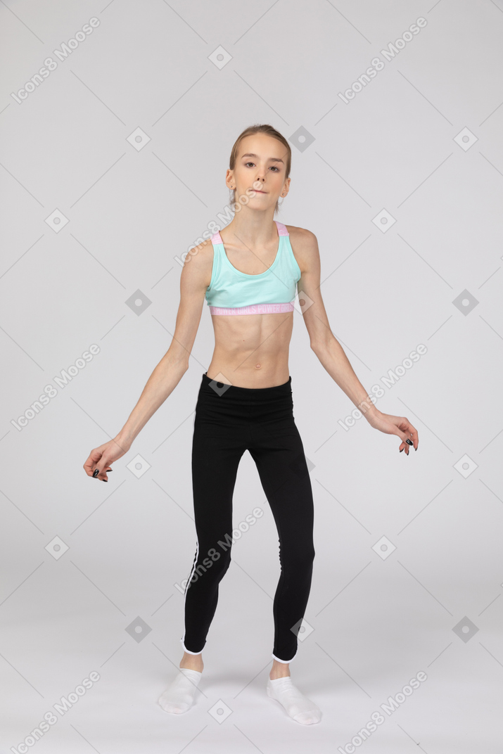 一个十几岁的女孩，在运动服伸展手中，看着相机的前视图
