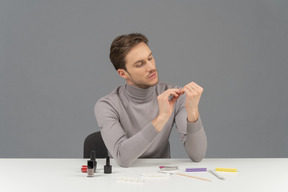 Un joven serio arreglando sus uñas