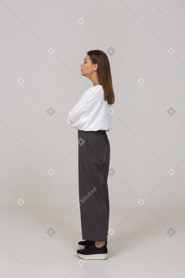 Vista laterale di una giovane donna seria in abiti da ufficio che guarda da parte