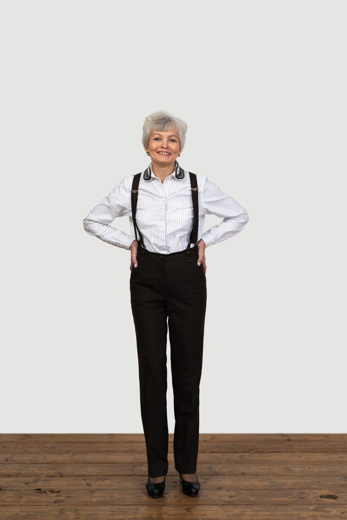 Full-length of a delighted old female in suspenders putting hands on hips