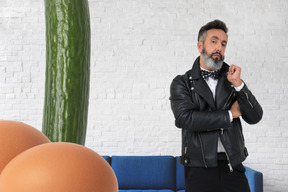 Hombre elegante de pie junto a un enorme pepino y huevos