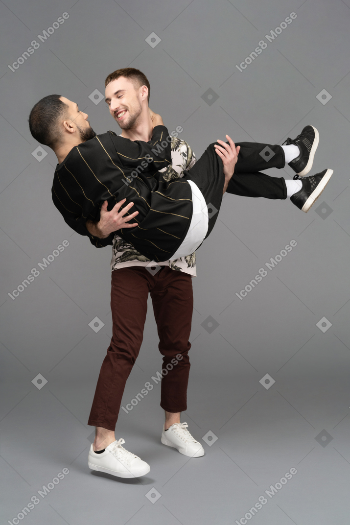 Young man smiling happily while holding another man bridal style